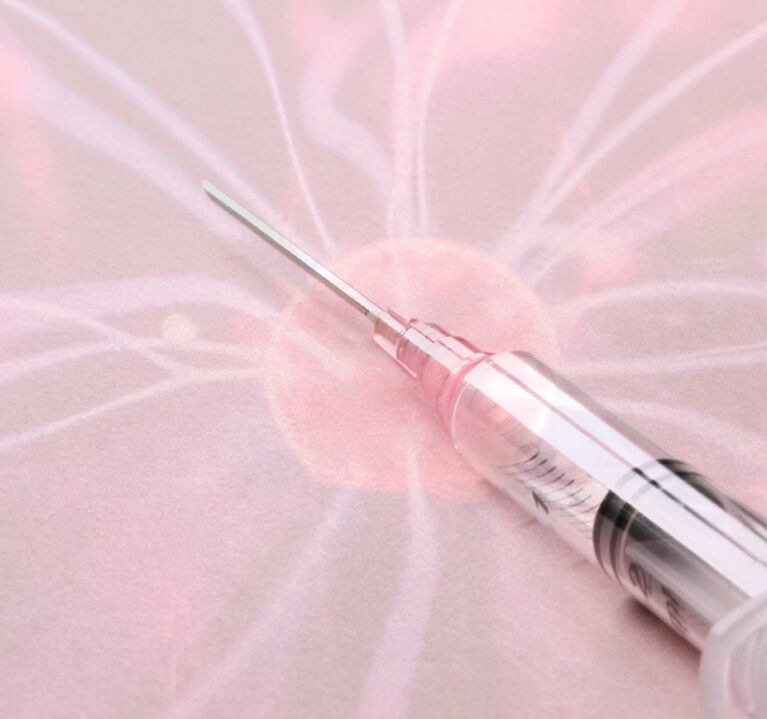 Eine Spritze mit Flüssigkeit auf rosa Hintergrund